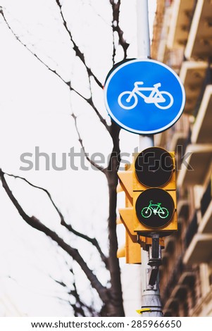 Round bicycle lane sign against a blue sky and blurred buildings at the background