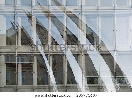 Close-up of modern glass facade of the building with reflection of an old building.