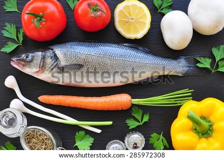 raw fish with fresh vegetables on a black background