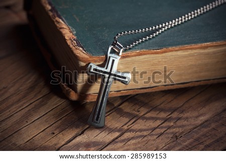Closeup of silver Christian cross on bible