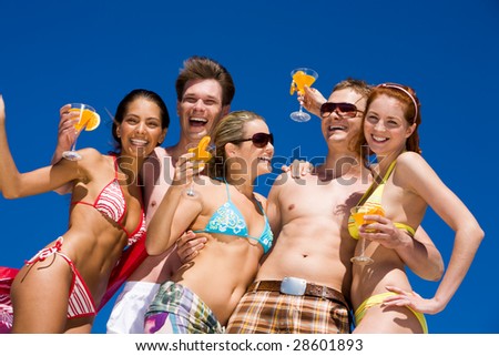 Photo of group of teens with cocktails in hands laughing while having party