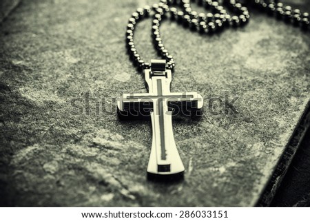 Closeup of silver Christian cross on bible