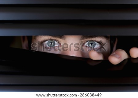 Young looking behind a blind, with eyes wide open. Royalty-Free Stock Photo #286038449