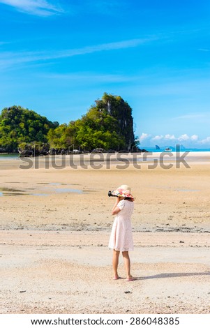 young female photographer takes photo of the beautiful beach
