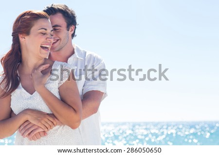 Happy couple hugging and laughing together at the beach