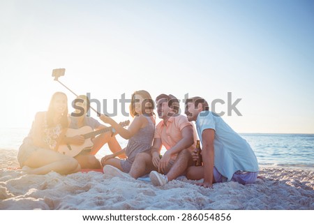 Happy hipsters taking pictures with selfie stick at the beach