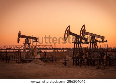 Pump jack group on a sunset sky background. Extraction of oil. Toned.