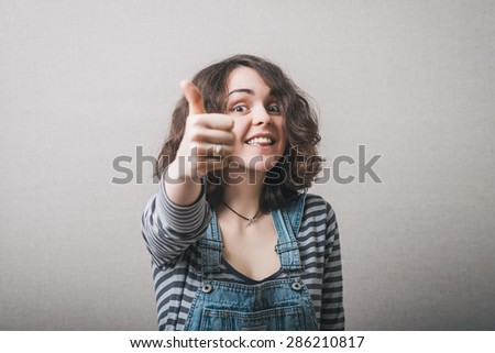 Woman showing thumbs up. On a gray background.