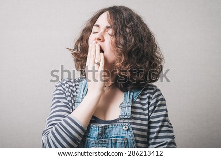 The woman yawns. On a gray background. Royalty-Free Stock Photo #286213412