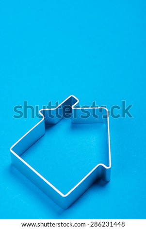 Funny metal house standing on a blue surface