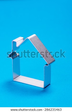Funny metal house standing on a blue surface