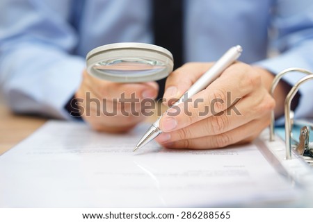 businessman is analyzing  through  magnifying glass contract and prices Royalty-Free Stock Photo #286288565