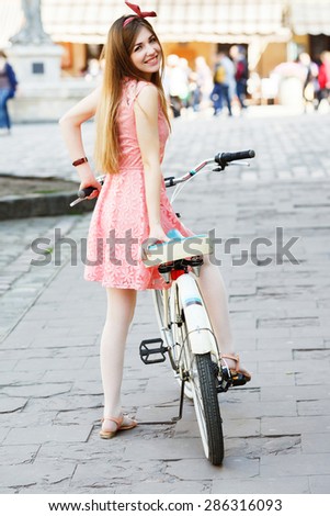 Young pretty blond-brown girl smiling in an center of old European city with vintage bicycle