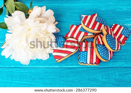 American patriotic cookies with white peony on the blue wooden background