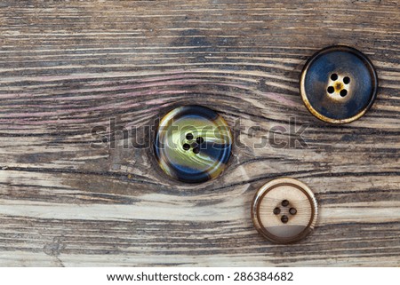 three old buttons on old textured wooden surface