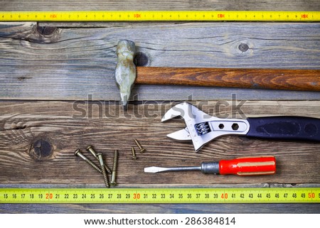 locksmith tools. old screwdriver, screws, monkey wrench, vintage hammer and tape-measure on the boards of the old workbench