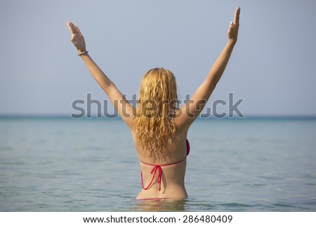 young woman with beautiful blonde hair meditating in sea on beach