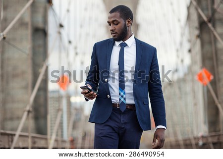 Young businessman using mobile phone on Brooklyn Bridge. New York City.