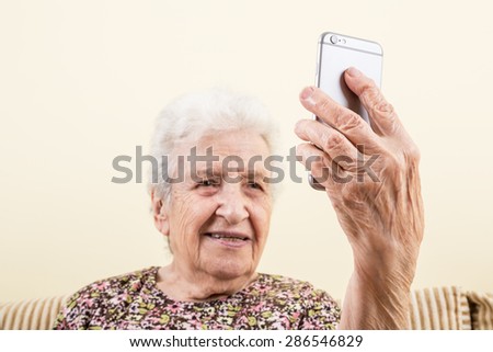 cell phone, a modern old senior woman taking selfie or making video call with mobile or cellphone on her hand. communication concept photo with old senior people at home