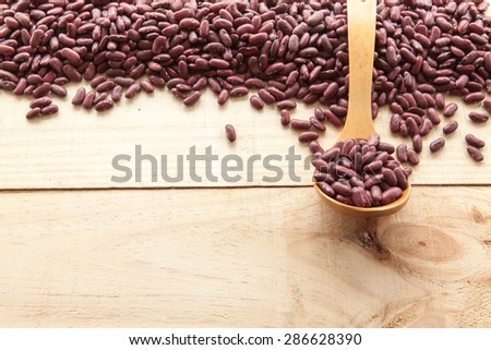 Wooden spoon and red beans seen from above on a wood background illuminated with a soft morning daylight