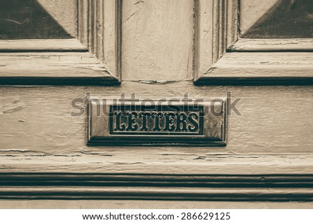 'Letters'  text engraved on a letterbox on a weathered door conceptual monochrome image