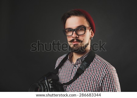handsome guy with beard and mustache with vintage camera on dark background in studio