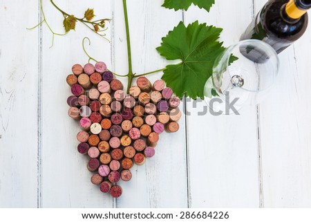 picture of stylized bunch of grapes with wine cork and glass and bottle of wine