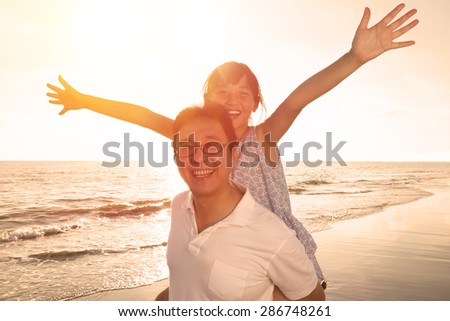 Father and daughter playing on the beach at the sunset