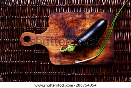 Creative picture of eggplant and one part of green onions on the rustic vintage cutting board