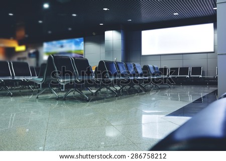 Blank billboard with clean space for publicity content or text message, advertising mock up in interior, public commercial board in waiting of airport hall with empty chairs, template banner indoors