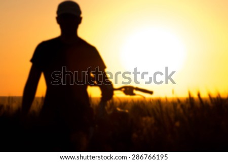 a young man in a field near a bicycle