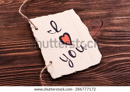 Inscription I LOVE YOU on cutout carton on wooden background