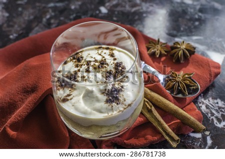 A creamy tiramisu dessert in a glass on a red napkin and marble surface
