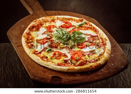 High Angle View of Fresh Baked Margherita Pizza Topped with Tomatoes, Cheese and Fresh Basil on Wooden Paddle