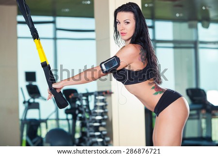 attractive woman does crossfit push ups with trx fitness straps in the gym's studio