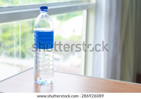 A bottle of pure water on the table near window, transparent plastic bottle and window background. Royalty-Free Stock Photo #286926089