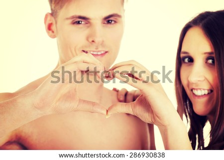 Happy young couple making heart with fingers.