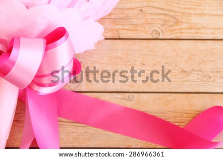 Pink ribbon on wooden background