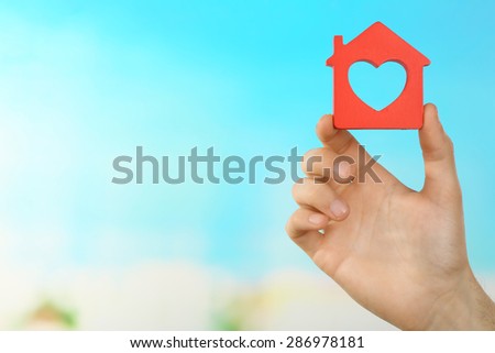 Female hand holding house on turquoise background