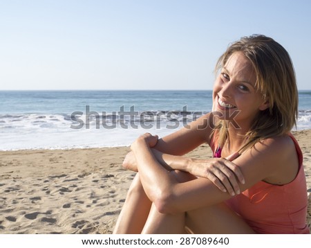 happy pretty woman smiling  in the beach  wearing a pink top with the sea and horizon in the background