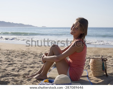 happy pretty woman smiling  in the beach  wearing a pink top, she have a beach bag, hat, a suncream, 