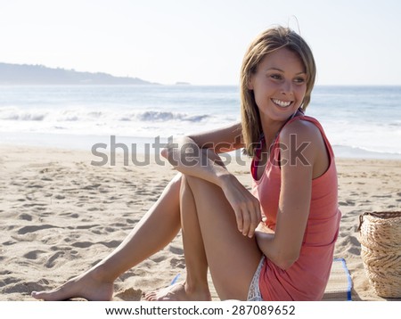 happy pretty woman smiling  in the beach  wearing a pink top with the sea and horizon in the background