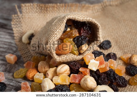 Nuts and dried fruits mix on a rustic sack and wooden background