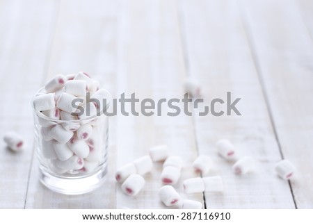glass of marshmallow on wooden white white background