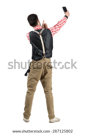 Young hipster male taking selfie with thumbs up rear view. Full body length portrait isolated over white studio background. 