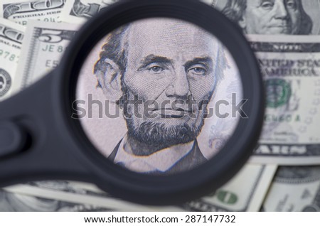   Lincoln on five dollar over heap of dollars United States as a background.