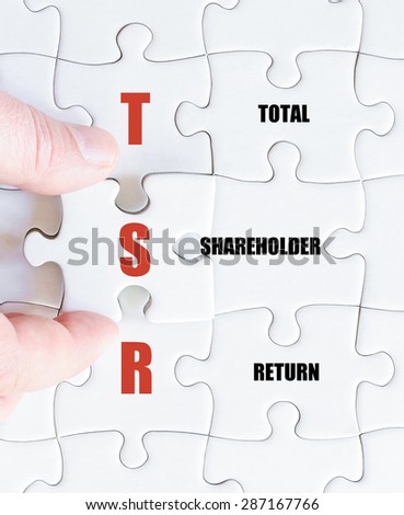 Hand of a business man completing the puzzle with the last missing piece.Concept image of Business Acronym TSR as Total Shareholder Return