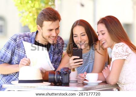 Group of three tourist friends planning vacation with a gps phone and a map in a coffee shop