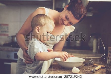 Mom with her 2 years old child cooking holiday pie in the kitchen to Mothers day, casual lifestyle photo series in real life interior Royalty-Free Stock Photo #287219243