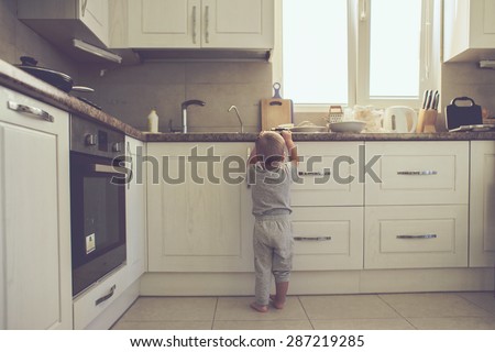 2 years old child standing on the floor alone in the kitchen, casual lifestyle photo series in real life interior Royalty-Free Stock Photo #287219285